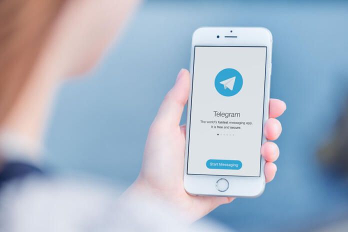 Mujer frente a un dispositivo móvil con la interfaz de Telegram