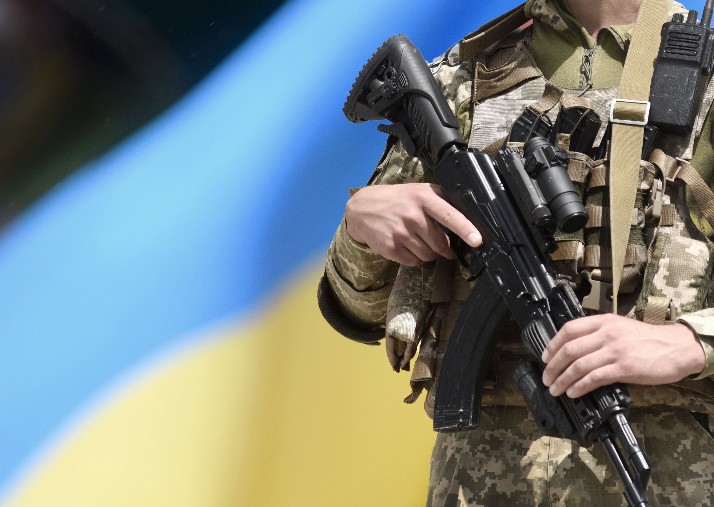 Soldado con un rifle de asalto ante la bandera de Ucrania