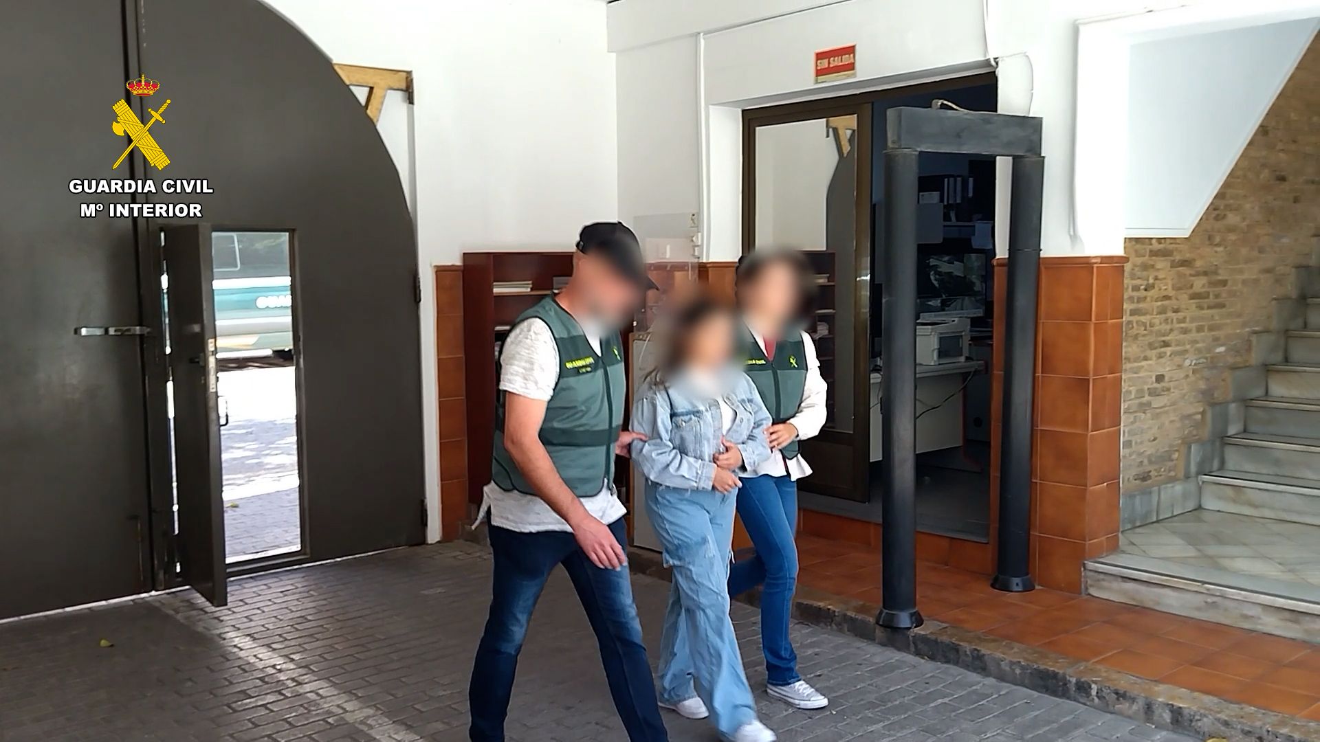 Agentes de la Guardia Civil con una de las cinco personas detenidas como presuntas integrantes de una organización criminal dedicada a la sextorsión