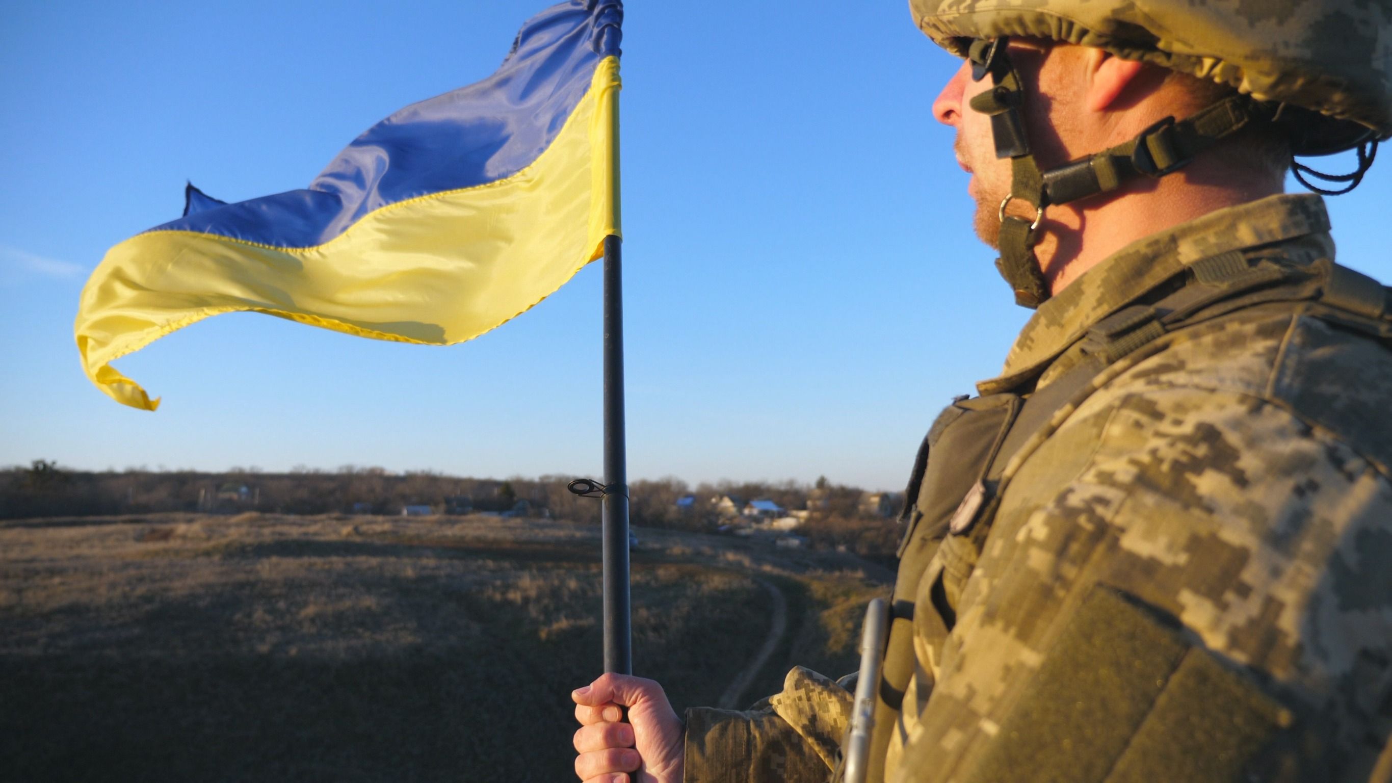 Soldado del ejército ucraniano sosteniendo la bandera ondeante de Ucrania.